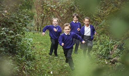 Four children running in forest school