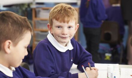 Child looking to camera whilst writing