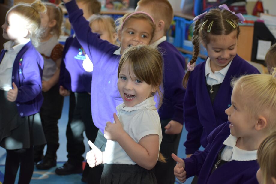 Smiling child giving a thumbs up in a crowd
