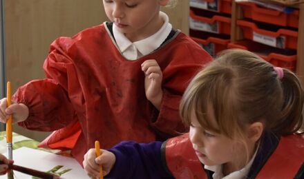 Children in red aprons painting