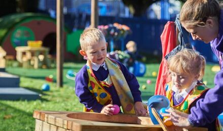 Children playing with a water table with teachers help