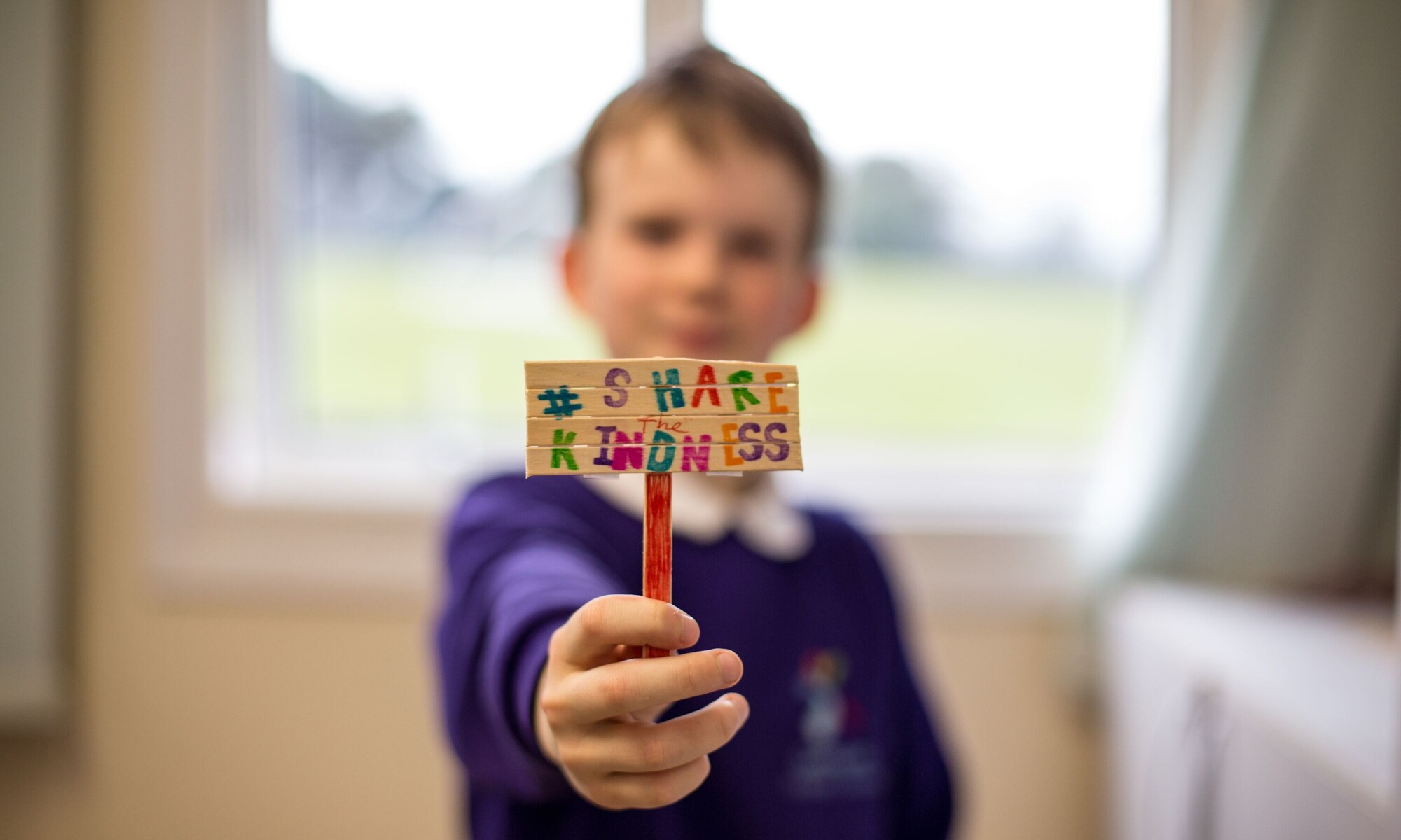 A child holding a sign that reads share the kindness