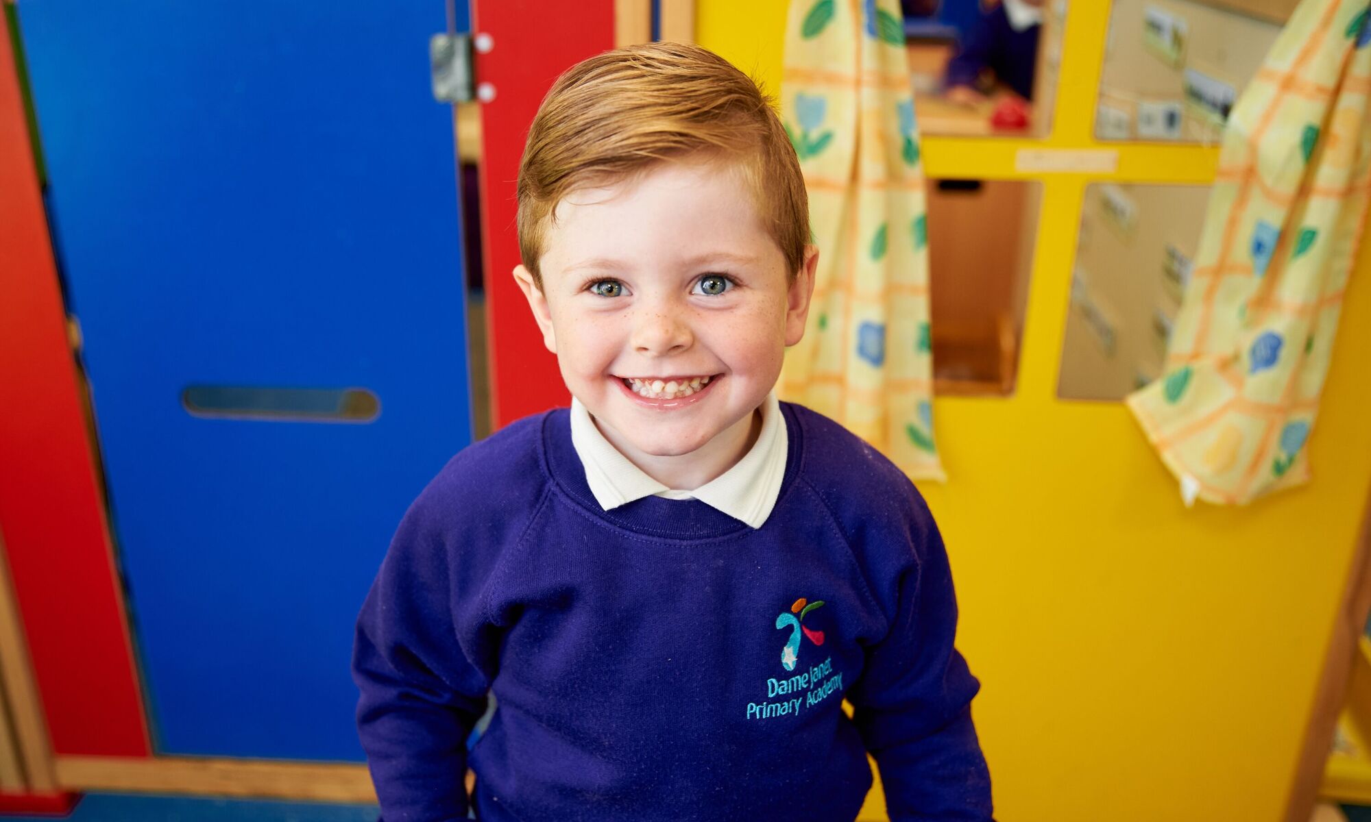 Child smiling at the camera with a bright background
